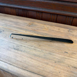 Flame On Main Wick Dipper in black metal resting on a wooden surface, designed for safely extinguishing candle flames, perfect for home decor and gifts from Knotty and Board. 1