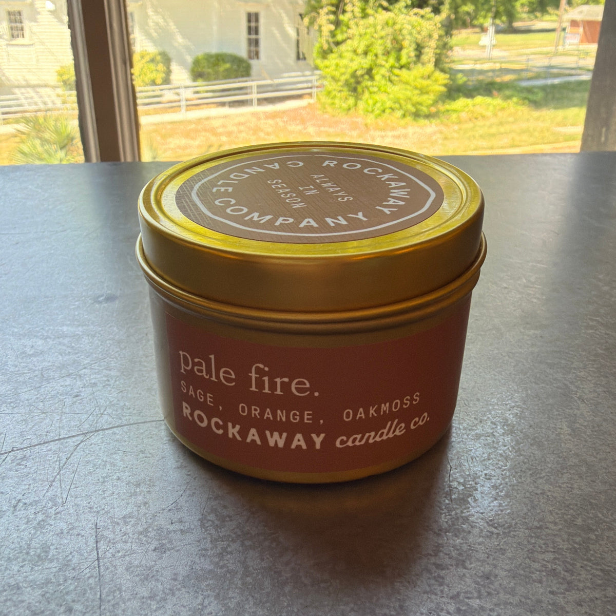 Rockaway Travel Candle 4oz Pale Fire features a sage, orange, and oakmoss scent in a compact tin, perfect for adding cozy decor and gift charm from Knotty and Board.