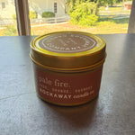 Rockaway Travel Candle 4oz Pale Fire features a sage, orange, and oakmoss scent in a compact tin, perfect for adding cozy decor and gift charm from Knotty and Board. 1