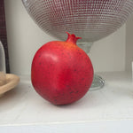 Pomegranate - Display sitting on a white shelf next to decorative glassware, perfect for adding a pop of color and unique decor to kitchen or dining spaces at Knotty and Board. 1