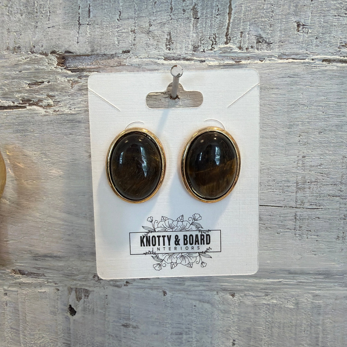 Oval Tiger Eye Stud Earrings with polished brown and gold stone set in a gold-tone frame, displayed on a Knotty and Board branded card for stylish jewelry gifts and decor.