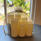 6 Pc Flameless LED Candles with Remote displayed inside a sheer drawstring bag on a table by a window, showcasing soft warm light for cozy home decor and entertaining by Knotty and Board.