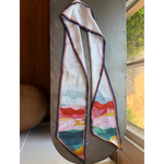 Agate Scarf, Multi-color with abstract watercolor design in tones of red, pink, green, and yellow, displayed on a rustic tabletop near a window, perfect for stylish decor or gifts from Knotty and Board. 1