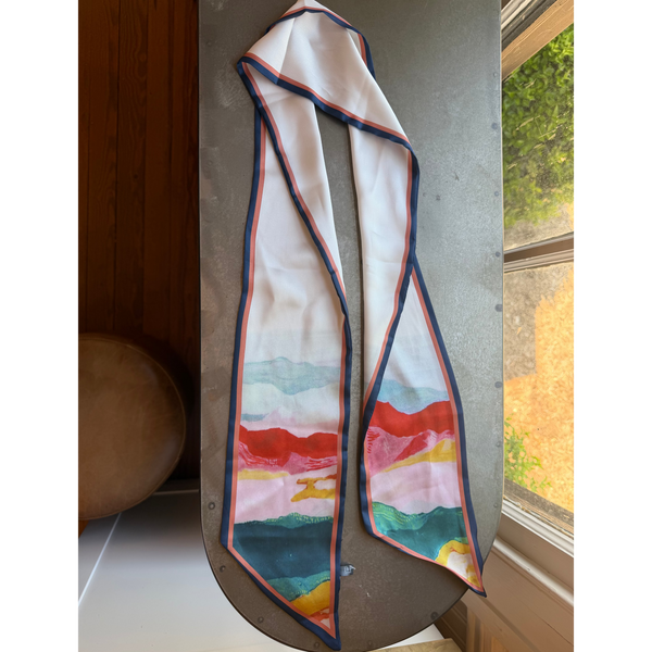 Agate Scarf, Multi-color with abstract watercolor design in tones of red, pink, green, and yellow, displayed on a rustic tabletop near a window, perfect for stylish decor or gifts from Knotty and Board.