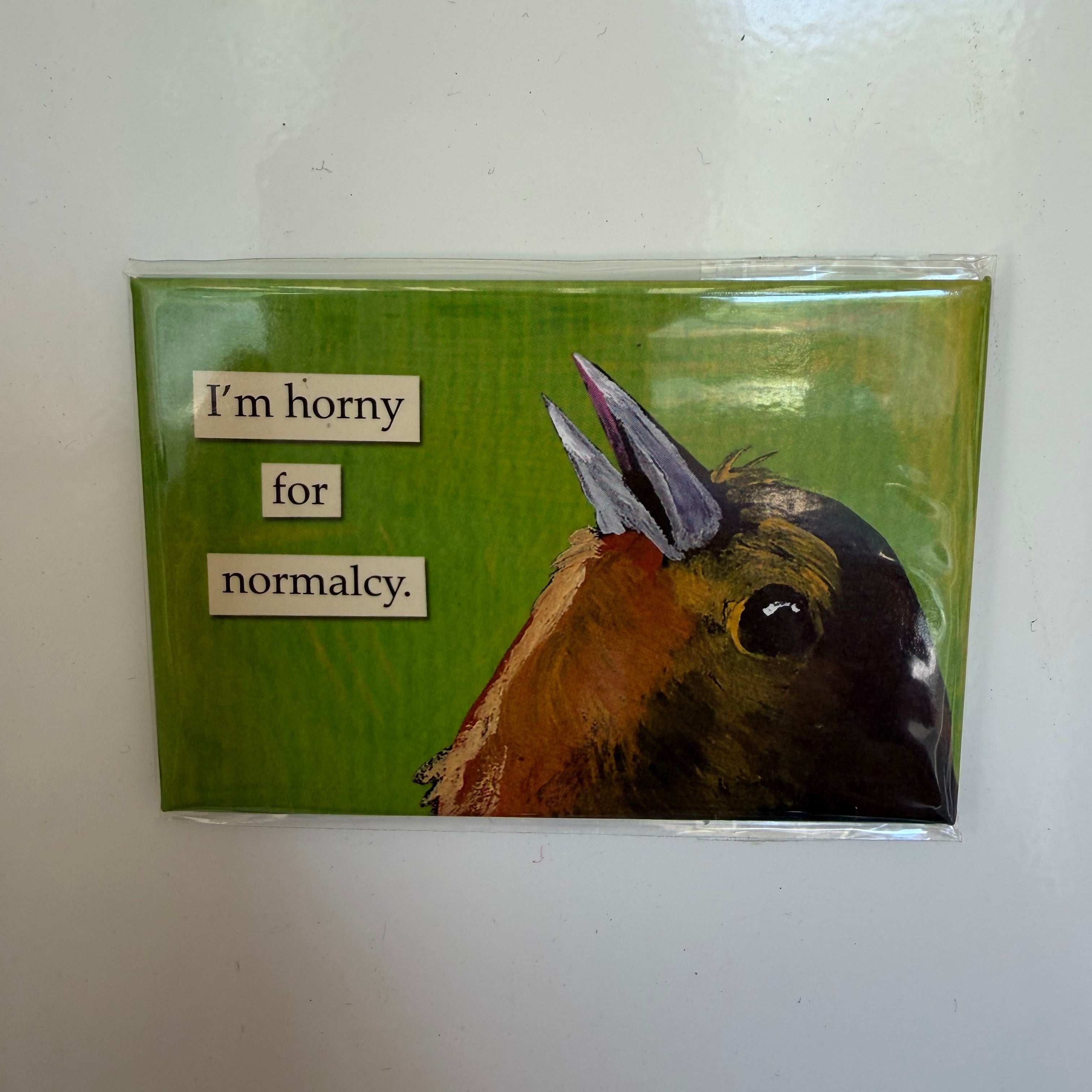 Funny Magnet, Horny For Normalcy featuring a humorous phrase next to a close-up illustration of a bird with prominent horns on a green background, perfect for quirky decor or gifts.