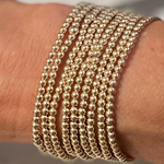 Morgan & Me 4mm 14k Gold Filled Bracelet wrapped multiple times on the wrist, showcasing shiny gold beads with elegant, timeless jewelry style from Knotty and Board. 1