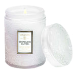 Voluspa Sparkling Cuvee Small Jar Candle, 5.5 oz burning in a textured white glass jar with the lid beside it, perfect for kitchen and dining decor or gifts from Knotty and Board. 1