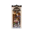 Intricate miniature diorama of a Parisian arcade scene featuring detailed shops, flowers, and cobblestone flooring in the Book Nook Kit: Paris Arcade Date with Dust Cover from Knotty and Board, perfect for unique home decor and gifts.