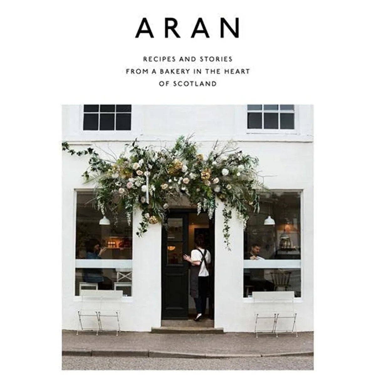 Cover of Aran: Recipes and Stories from a Bakery in the Heart of Scotland - Flora Shedden featuring a charming bakery entrance adorned with lush floral decor, reflecting Knotty and Board’s curated gifts and kitchen ambiance.