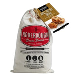A natural cotton bag of Soberdough Brew Bread, Apple Fritter artisan beer bread mix with a label showing bread pieces, perfect for kitchen or gift decor from Knotty and Board. 1