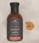 Bottle of Finch & Fennel Ole' Smokehouse Moppin' Sauce, 13.5 oz, with a sample of the savory basting sauce on a light surface, ideal for kitchen and entertaining gifts. 1