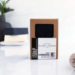 Men's Soap, Hardworking Man, Plum Amber Citrus, 5 oz. in eco-friendly brown packaging with black and white label, displayed on a clean surface with blurred decor in the background. 1