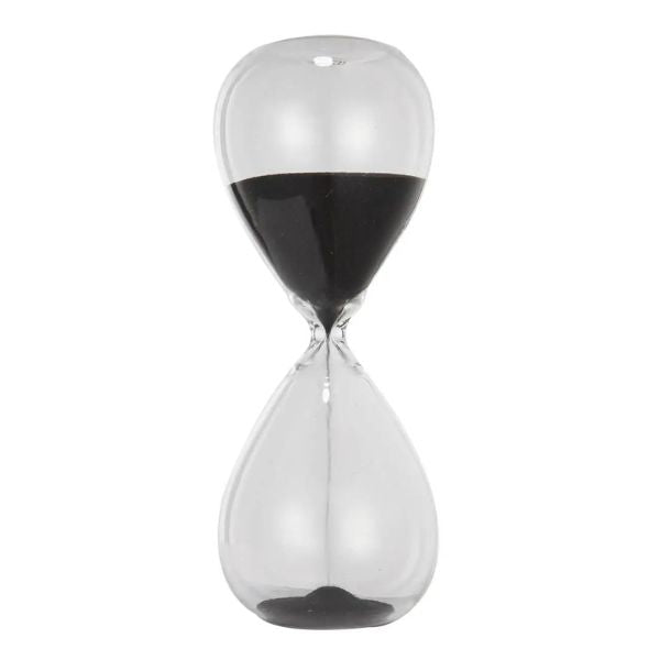 Clear glass hourglass with black sand measuring 15 minutes, an elegant decor piece featured in the Ferdinand 15-minute Hourglass, Black, 7 in. collection, ideal for gifts and home accents.