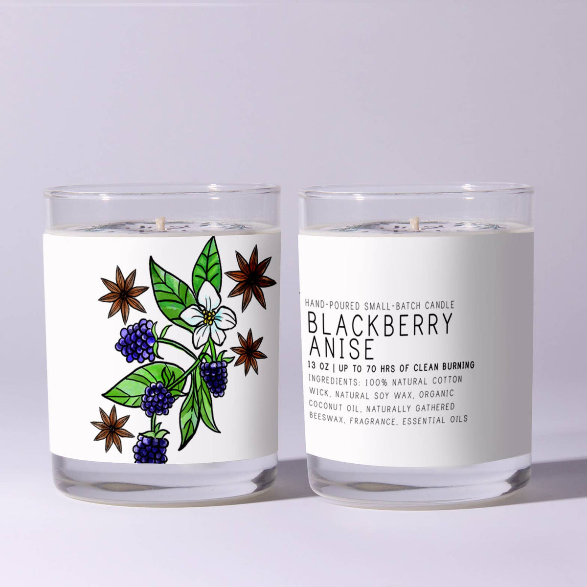 Two clear glass candles with white wax, one showing a colorful botanical illustration of blackberries, anise stars, and green leaves, the other displaying product text for Just Bee Blackberry Anise, 7 oz, on a light gray background.