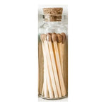 A glass vial filled with long, brown-tipped safety matches sealed with a cork stopper, perfect for decor or gifting from Knotty and Board. Every Room Needs A Little Knotty and Board. 1