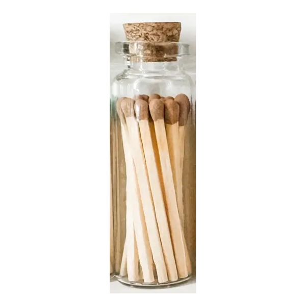 A glass vial filled with long, brown-tipped safety matches sealed with a cork stopper, perfect for decor or gifting from Knotty and Board. Every Room Needs A Little Knotty and Board.