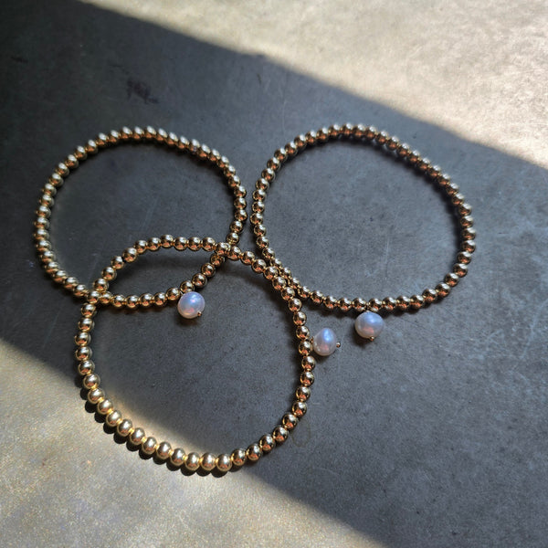 Morgan & Me 4mm 14k Gold Filled Bracelet with Pearl displayed in natural light on a textured surface, highlighting delicate gold beads and elegant pearl accents.