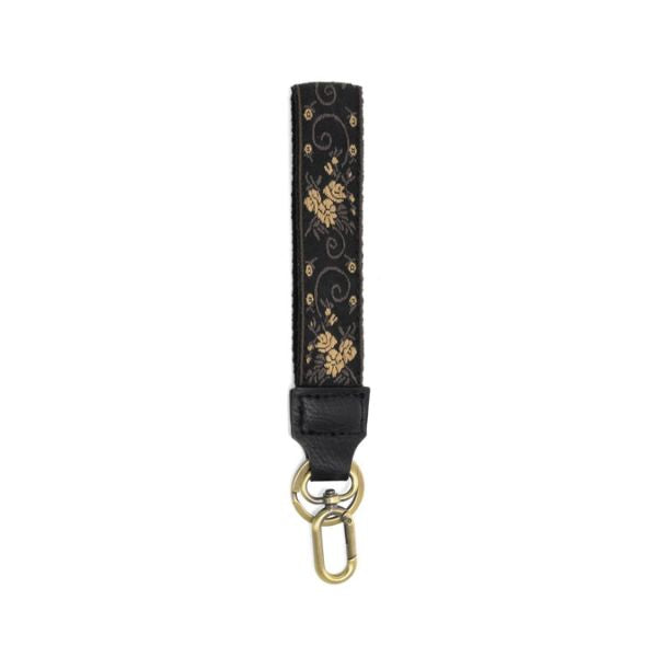 Easy Find Wristlet, Neutral Scrolling Floral featuring a black fabric strap with gold floral scroll patterns and a gold-tone clasp, perfect for stylish gifts and everyday use.