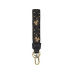 Easy Find Wristlet, Neutral Scrolling Floral featuring a black fabric strap with gold floral scroll patterns and a gold-tone clasp, perfect for stylish gifts and everyday use. 1