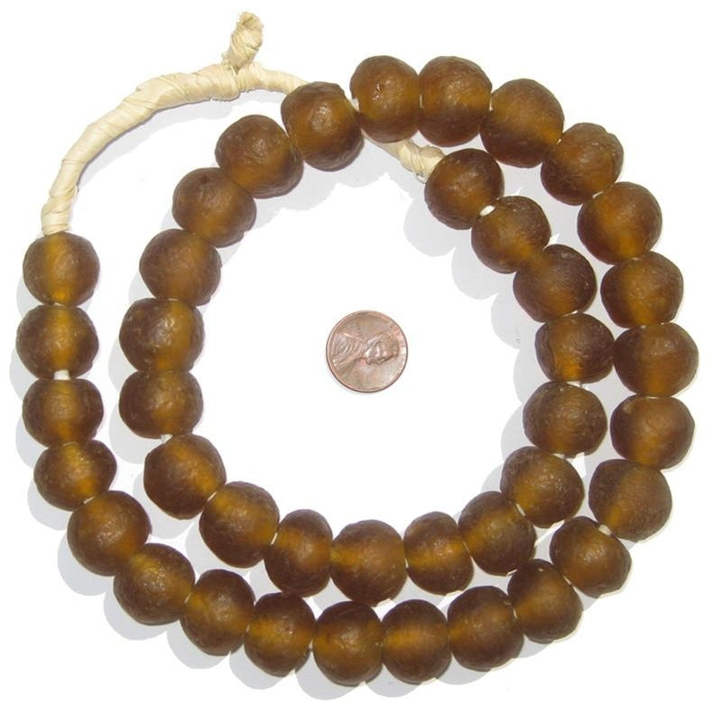 Close-up of brown Recycled Glass Beads 18 mm Assorted Colors arranged in a circle around a penny, highlighting handmade decor and jewelry elements from Knotty and Board.