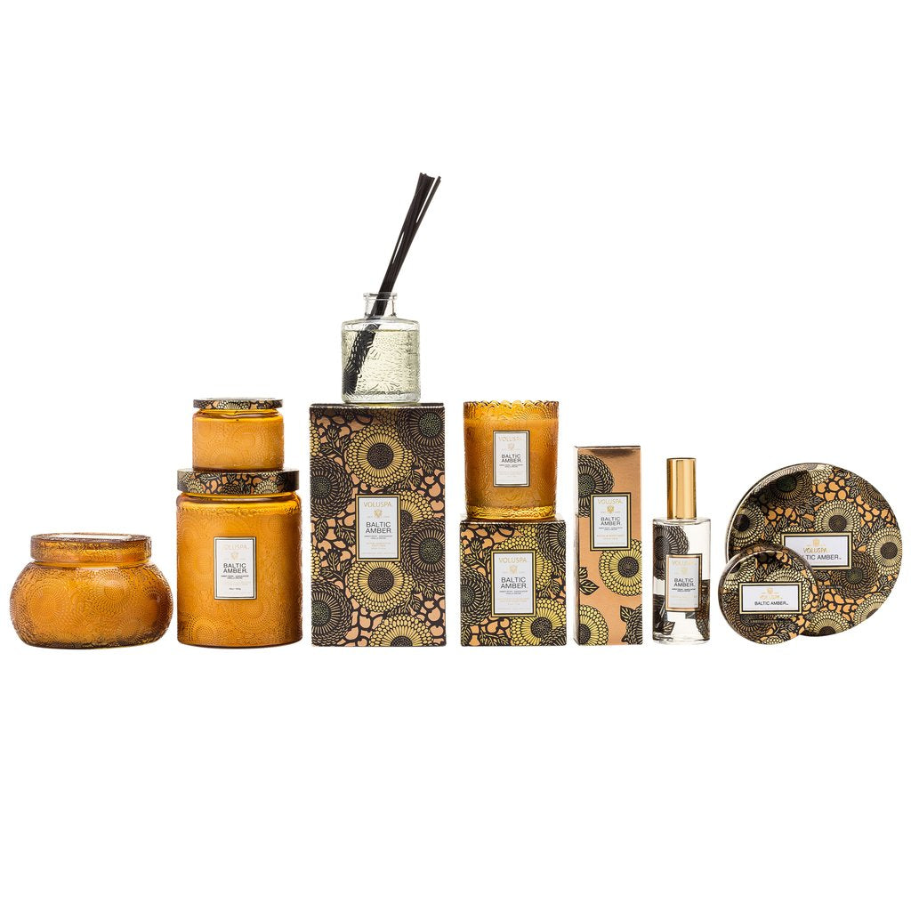 Voluspa Baltic Amber Reed Diffuser, 3.4 fl oz displayed with coordinating amber-colored candles and decorative packaging, perfect gifts and decor from Knotty and Board.