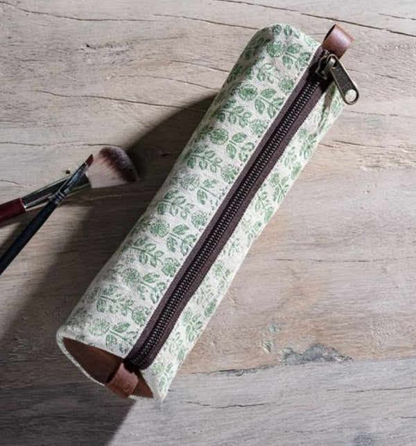 Green Floral Canvas Pencil Case 8.5" with a leafy pattern and brown zipper, displayed on a wooden surface alongside two makeup brushes, enhancing decor and gifting options.