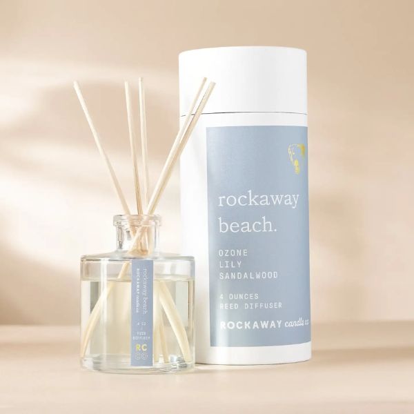 Rockaway Beach Reed Diffuser with clear glass bottle, natural reeds, and light blue labeled packaging, perfect for adding fresh decor and fragrance to any room.