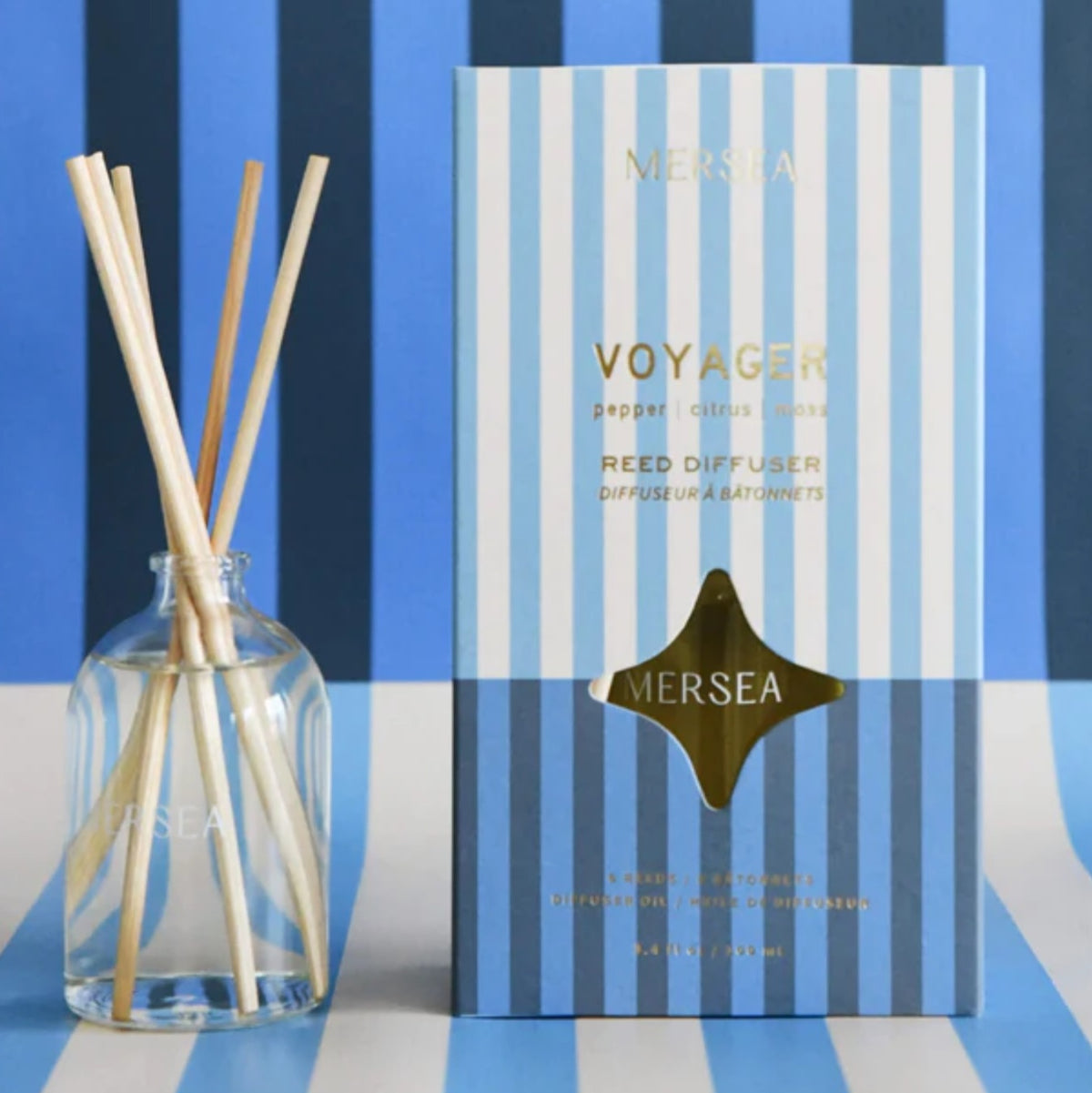 Mer-Sea Voyager, Room Diffuser, 3.4 oz displayed with natural reed sticks and striped blue packaging, a stylish decor piece perfect for gifting and enhancing any room ambiance.