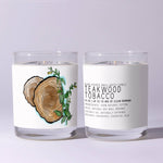 Two clear glass candles labeled Just Bee Teakwood Tobacco - 7 oz featuring wood grain and greenery illustration, perfect for rustic decor and gifts from Knotty and Board. 2