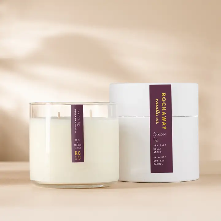 Rockaway Folklore Fig Candle 16oz displayed with white packaging and glass jar on a beige background, perfect for home decor and thoughtful gifts from Knotty and Board.