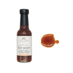 Peach + Onion Hot Sauce, 5 oz bottle with a sample of the hot sauce showcasing its rich, reddish-brown color, perfect for kitchen and dining use from Knotty and Board. 1