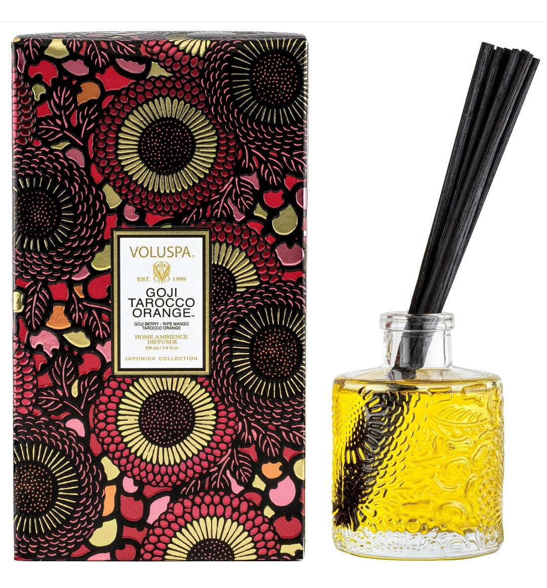 Voluspa Goji Tarocco Orange Reed Diffuser 3.4 oz with black reeds in a textured glass bottle filled with yellow liquid, next to a colorful floral patterned box, perfect for kitchen or dining decor from Knotty and Board, Every Room Needs A Little Knotty and Board.