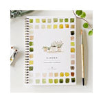 Cover of the Watercolor Workbook, Garden featuring a spiral-bound design with watercolor paint swatches in green and yellow tones, a paintbrush, and a plant nearby, reflecting Knotty and Board’s curated decor and gifts aesthetic. 1