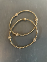 Morgan & Me 4mm 14k Gold Filled Bracelet with 14k Gold or Sterling Silver Bead displayed on a dark surface, showcasing delicate gold beads with textured accent beads, a perfect jewelry gift from Knotty and Board. 1