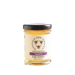 A 3 oz. jar of Savannah Bee Co., Tupelo Raw Honey with a black lid, featuring a simple label displaying bees and natural honey tones, ideal for kitchen gifts and decor. 1