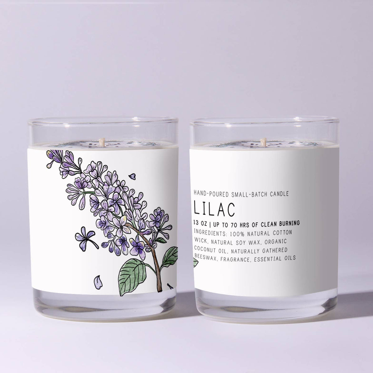 Two clear glass jars with hand-poured Just Bee Lilac Candle, 7 oz featuring a delicate lilac flower illustration and natural soy wax ingredients, showcased for decor and gifts.