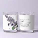 Two clear glass jars with hand-poured Just Bee Lilac Candle, 7 oz featuring a delicate lilac flower illustration and natural soy wax ingredients, showcased for decor and gifts. 2