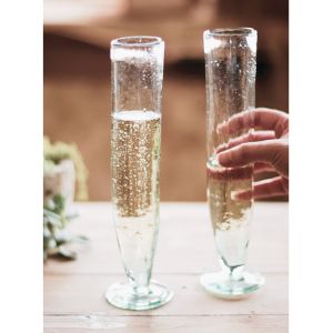 Two Recycled Tall Champagne Flute glasses with sparkling beverage, one being held, showcasing elegant design for dining and entertaining decor from Knotty and Board.