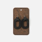 Oval Earrings, Black displayed on a rustic textured card, perfect for adding a modern touch to any jewelry collection with stylish elegance from Knotty and Board. 1