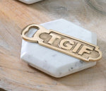 Brass TGIF Bottle Opener resting on a white marble hexagonal coaster on a wooden surface, perfect for kitchen or entertaining decor. 1