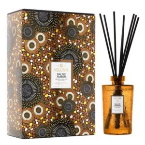 Voluspa Baltic Amber Reed Diffuser, 500 mL in an amber glass bottle with black reeds, next to a decorative patterned box, perfect for gifts and home decor from Knotty and Board.