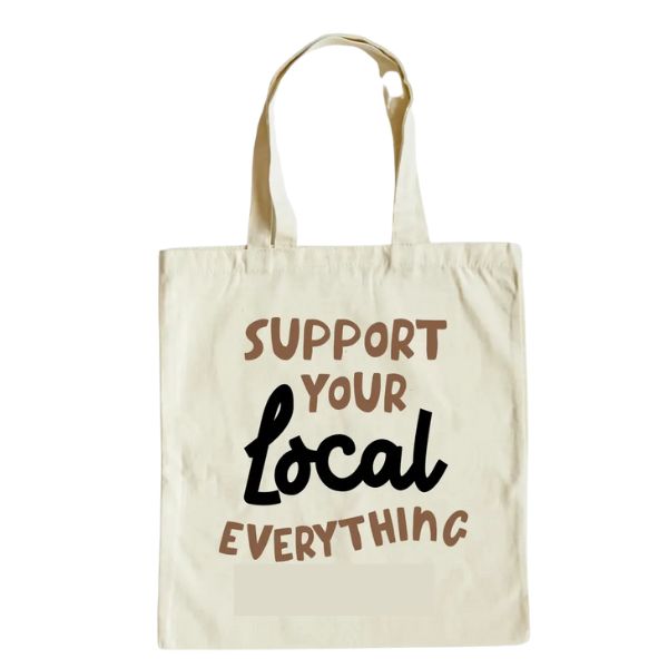 Natural canvas bag with long handles featuring the phrase "Support Your Local Everything" in playful brown and black lettering, ideal for decor and gifts from Knotty and Board.