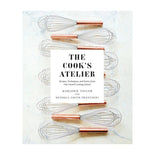 Cook's Atelier Book pictured with copper-handled whisks on a marble surface, highlighting kitchen decor and culinary inspiration from Knotty and Board, an independent brick and mortar retail. 1