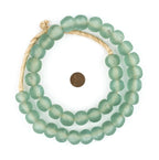 A strand of frosted light green Recycled Glass Beads 18 mm Assorted Colors displayed in a loose coil next to a penny for size comparison, perfect for jewelry or decor.