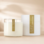 Rockaway Fig & Vine Candle 16oz in a clear glass container with white wax beside its elegant white cylindrical packaging, styled as curated decor and gift from Knotty and Board. 1