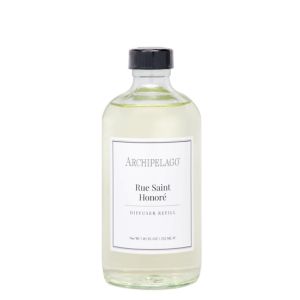 Clear glass bottle of Archipelago Rue Saint Honore Diffuser Oil Refill, 7.8 oz, with black cap and minimalist white label, elegant home decor gift solution from Knotty and Board.