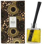 Voluspa Baltic Amber Reed Diffuser, 3.4 fl oz with amber-colored fragrance oil in a textured glass bottle and decorative black floral packaging, perfect for decor and gifts from Knotty and Board.